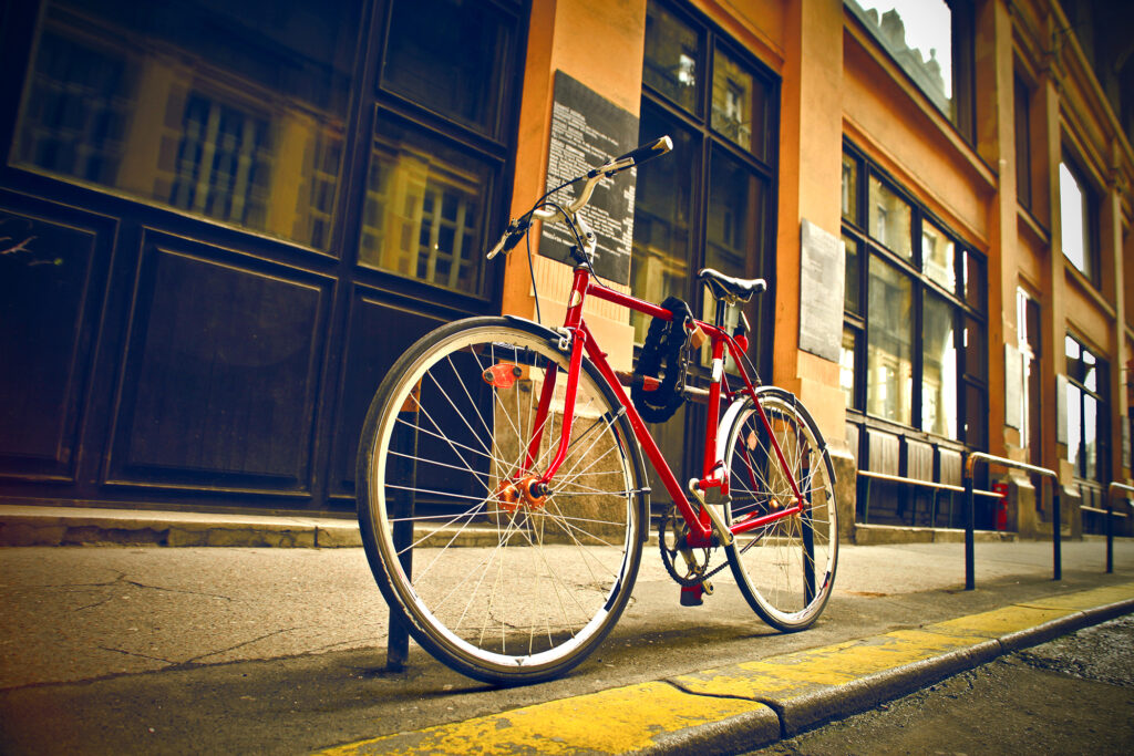 Red bicycle parked on an urban sidewalk, highlighting bike safety and parking regulations for cyclists.