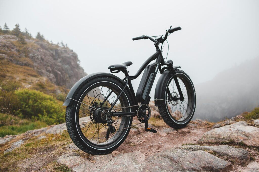 Electric mountain bike on a rocky trail with misty hills in the background, highlighting e-bike design and terrain capability.