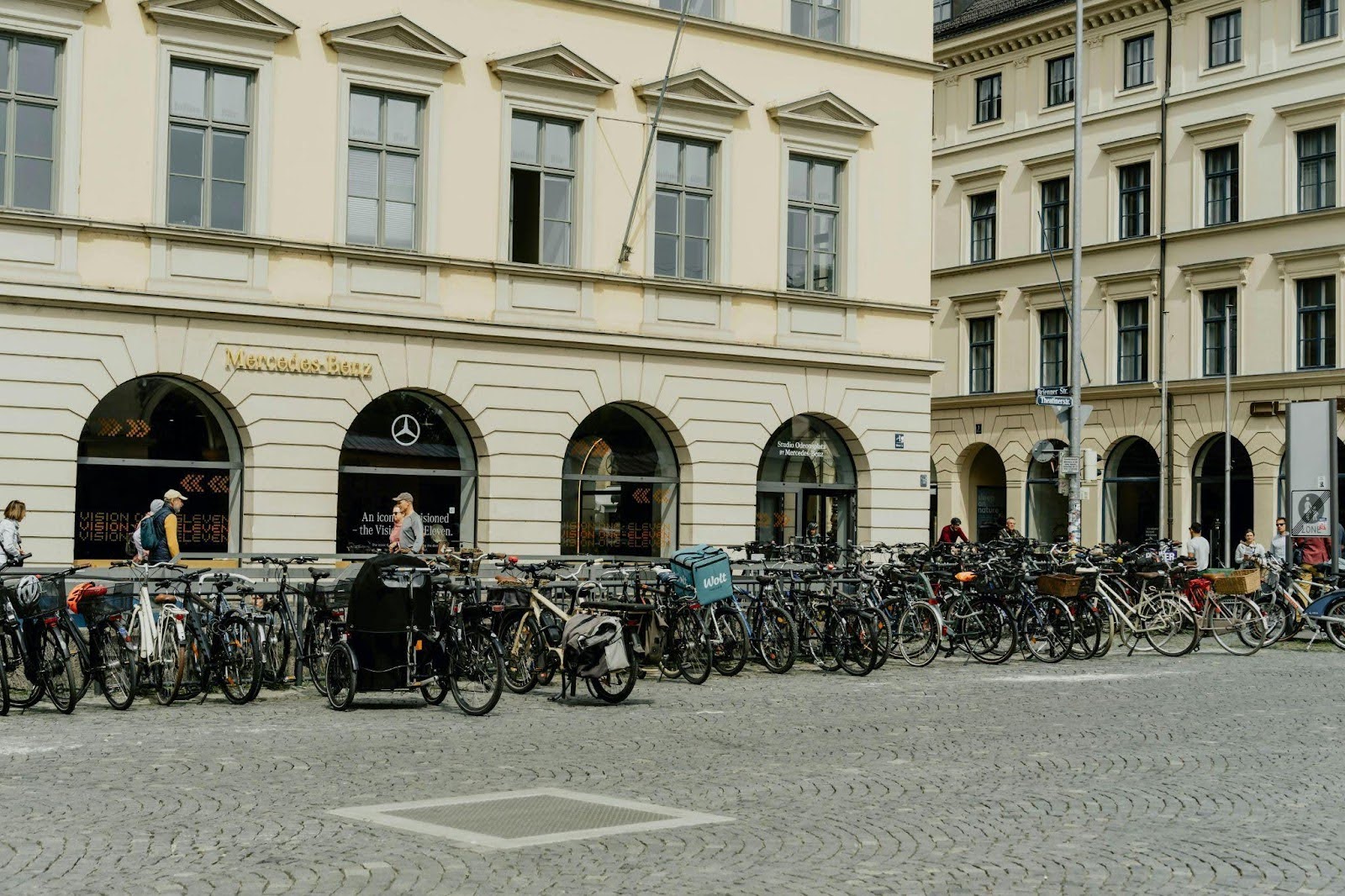 Rows of bicycles parked outside a Mercedes-Benz showroom in a European city.