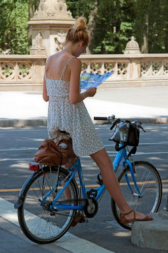 A woman checks a map while standing next to her bicycle, representing cyclists who may face injuries while riding out of state.