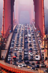 Cars packed on the Golden Gate Bridge during peak-hour traffic with pedestrians walking beside them.