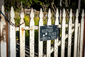 Fence gate with sign asking to keep closed due to dogs inside yard posing risk to passing cyclists