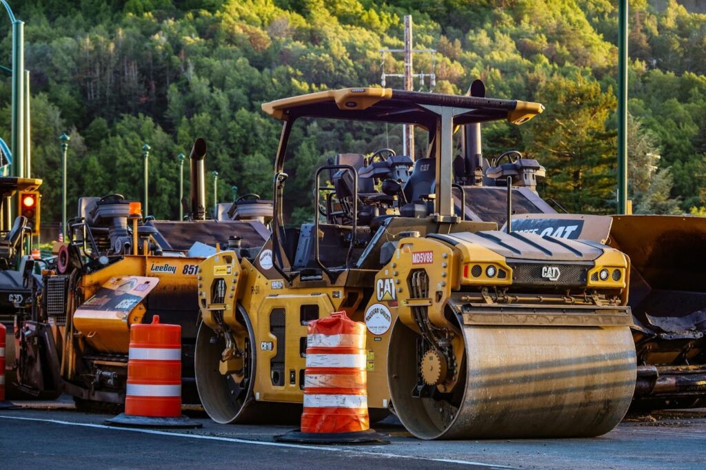 Steam roller working in a road construction zone with orange traffic cones marking a closed bike lane